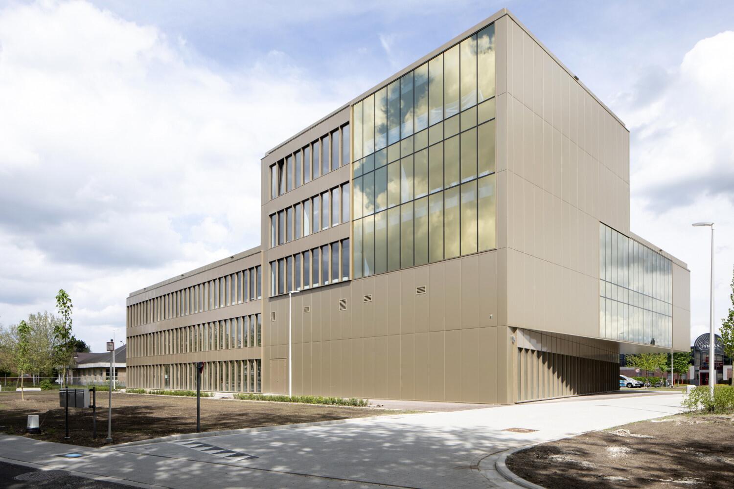Modern gebouw met glazen gevel en wolkenlucht.