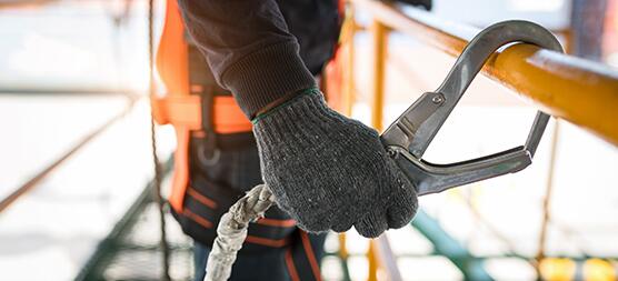 Persoon in veiligheidsvest bevestigt haak aan reling.