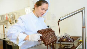 Chocolatier giet vloeibare chocolade in een mal in een keuken.