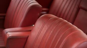 Rode leren autostoelen met verticale stiksels.
