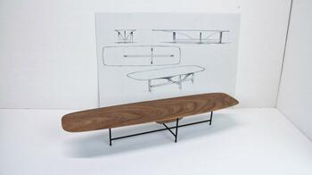 Lange houten tafel met metalen poten, voor witte achterwand.