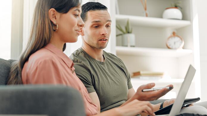 Man en vrouw werken samen op een laptop in een lichte kamer.