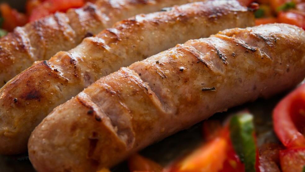 Gegrilde worsten met groenten in een pan.