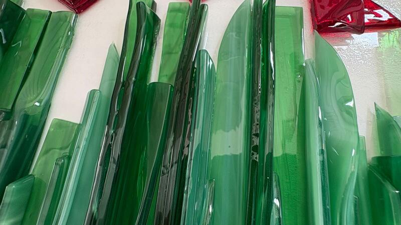 Groene en rode glazen stukken op een witte achtergrond.
