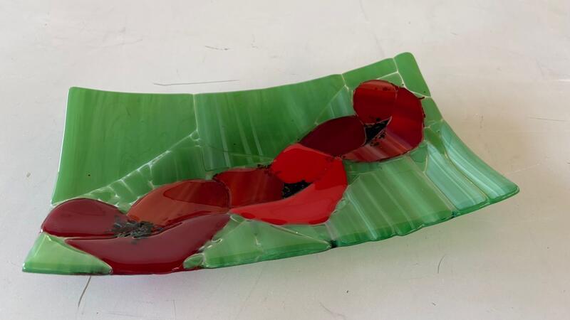 Groen bord met rode glazen bloemen.